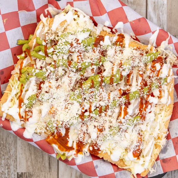 El Chapin's Mexican tostada with shredded lettuce, guacamole, sour cream, cheese, and red sauce.